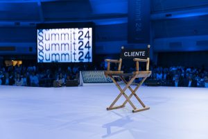 Cadeira no palco do BTG Summit 2024 com a palavra "cliente" inscrita no encosto.