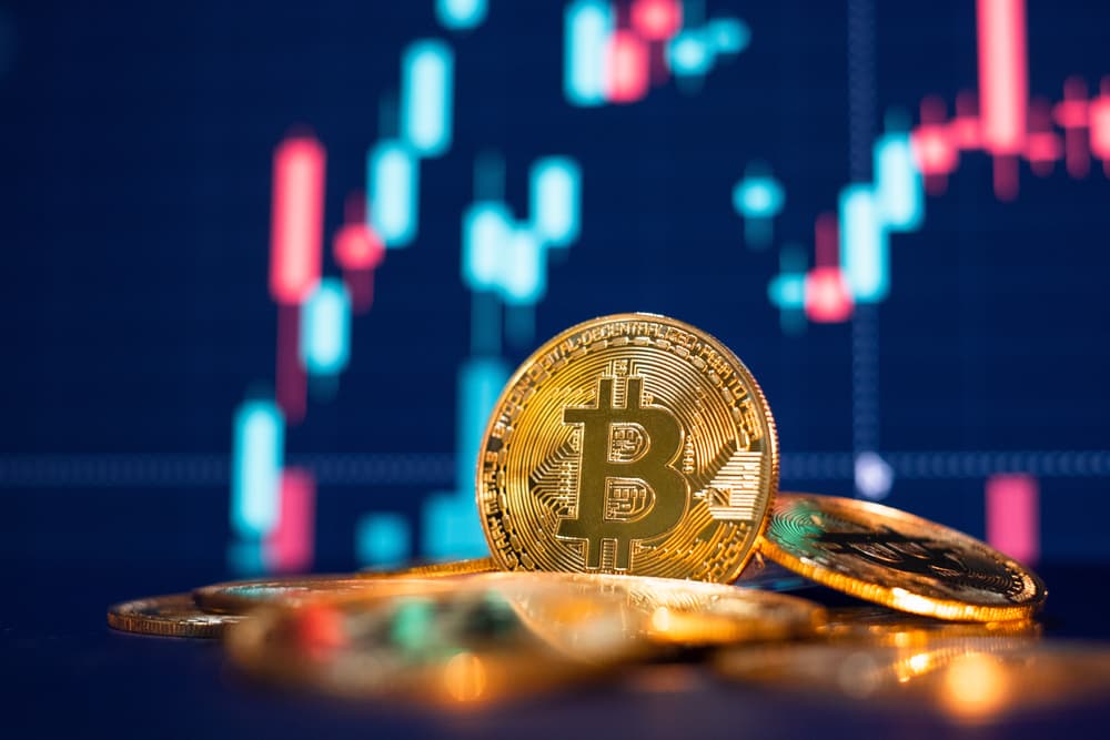 Bitcoin com gráfico ao fundo, simbolizando oscilações de mercado.