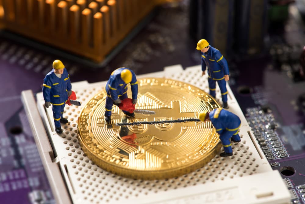 Reprodução de trabalhadores em miniatura minerando um bitcoin pela metade, simbolizando o halving.