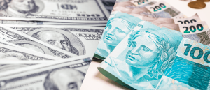 Notas de dólar e de real em tela dividida, representando o câmbio entre elas.