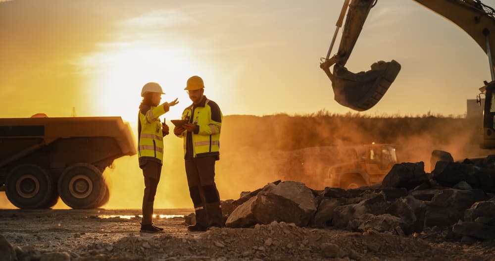 Dois trabalhadores conversando em um terreno de mineração.