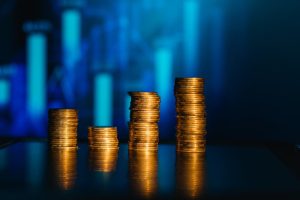 Moedas empilhadas com gráfico no fundo demonstrando o cálculo do lucro real