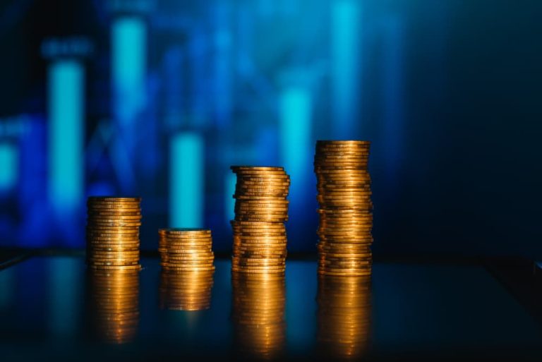 Moedas empilhadas com gráfico no fundo demonstrando o cálculo do lucro real