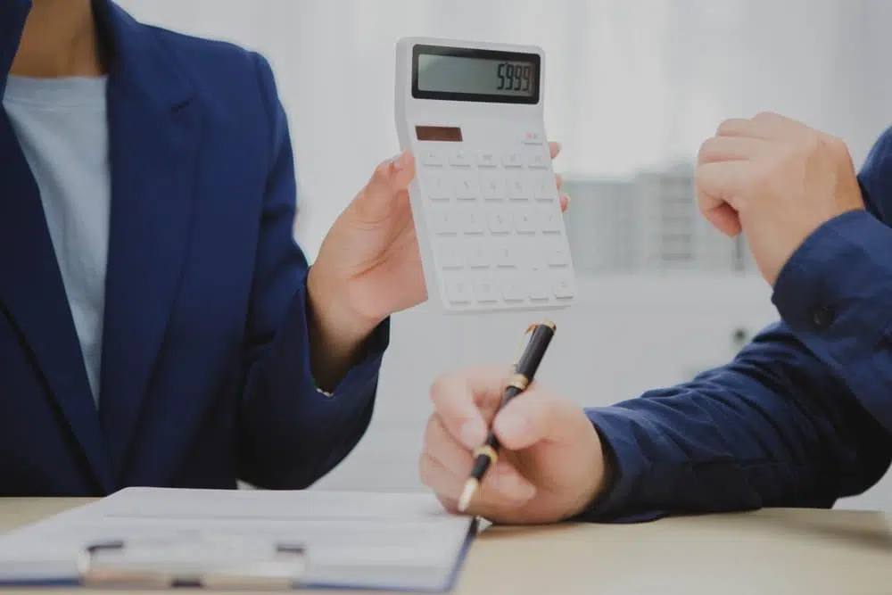 mão do consultor mostrando calculadora e os seus cálculos com os Regimes Tributários no Brasil