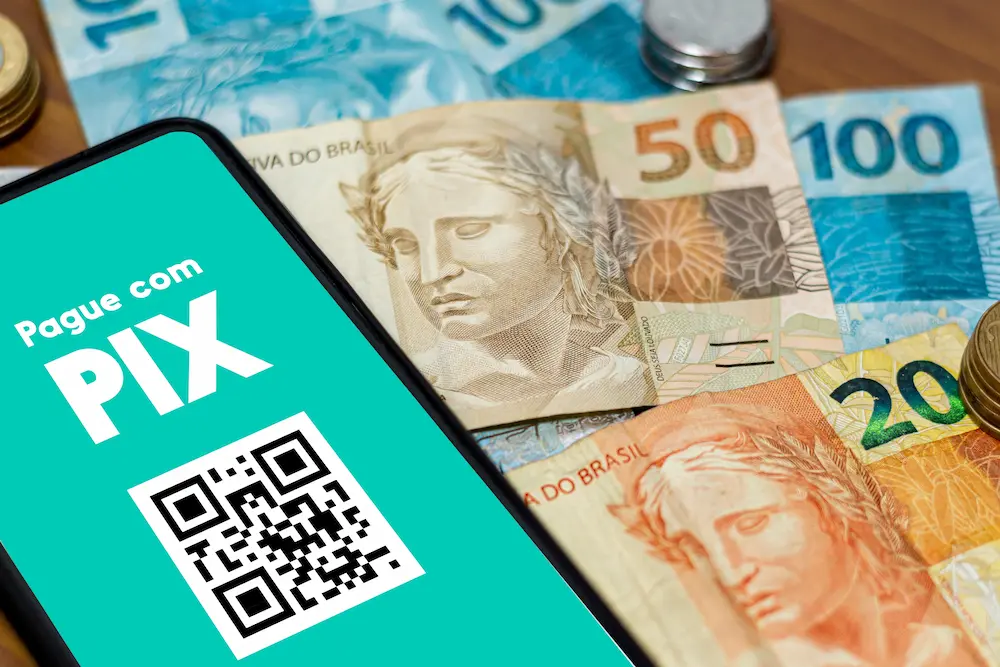 tela de celular com pix automático e notas de dinheiro ao fundo