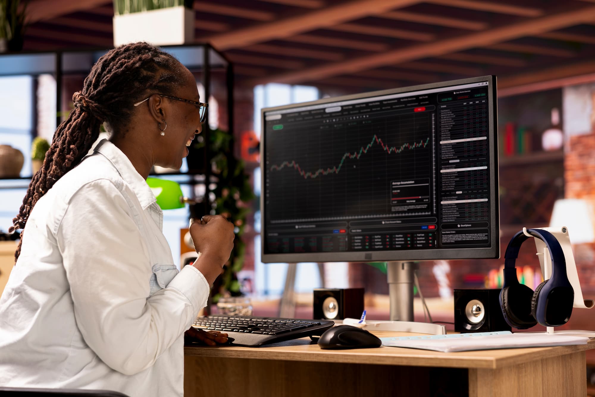 imagem mostra uma mulher investidora sentada e sorrindo olhando a tela do home broker.