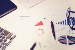 FIDC: o que é e como funciona esse tipo de investimento imagem mostra uma mesa de trabalho com caneta, composição de fundo de investimento e óculos.