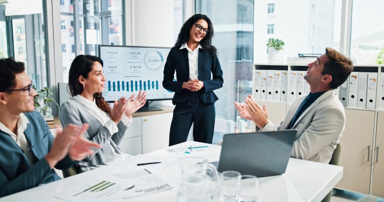 imagem mostra quatro pessoas reunidas em uma sala de escritório comemorando os resultados de investimentos.