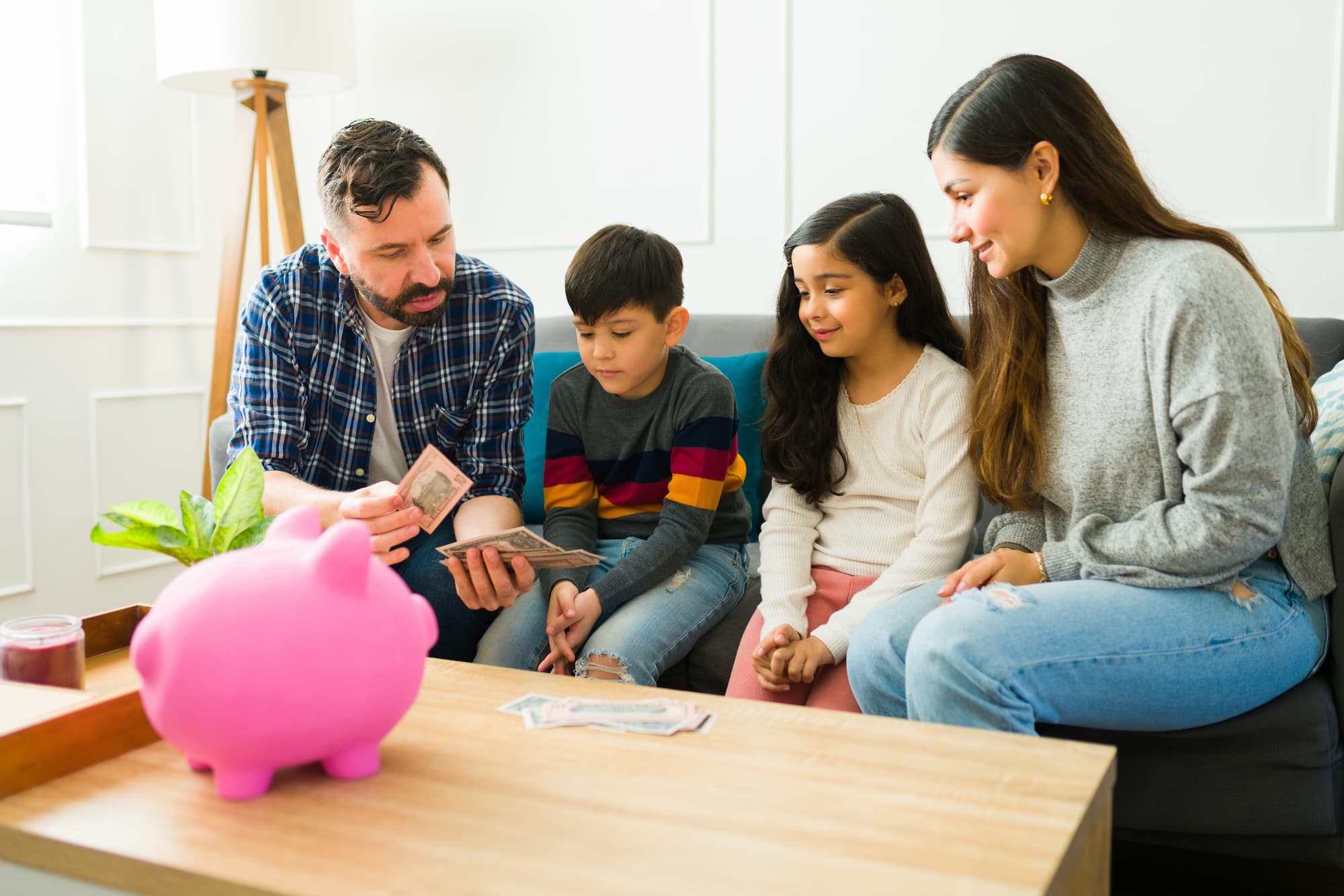 imagem mostra uma família reunida e os pais ensinando sobre educação financeira para os filhos.