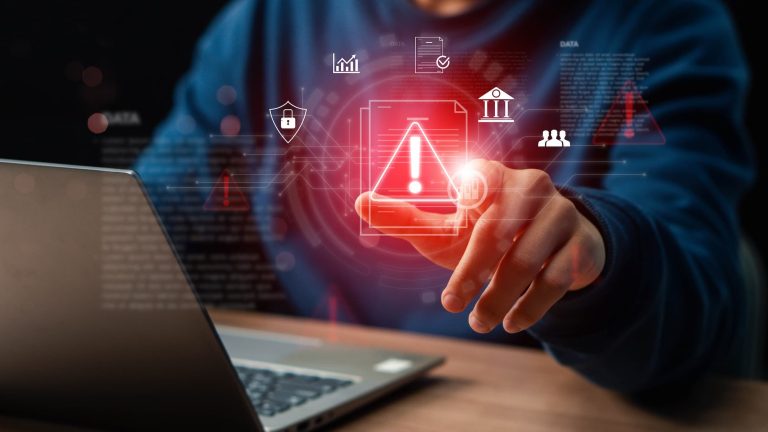 imagem mostra um homem com um sinal de alerta em frente ao seu notebook.