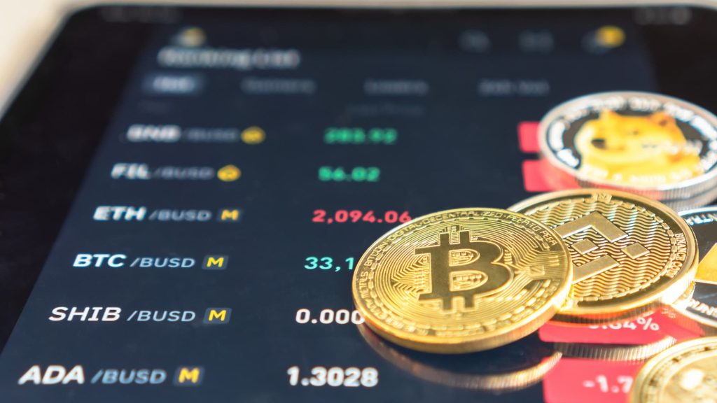 imagem mostra moedas de bitcoin e cotações de criptoativos