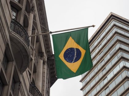 Bandeira brasileira hasteada em fachada de prédio.